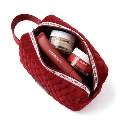 Kit de skincare com nécessaire vermelha, balm labial e esfoliante para lábios.