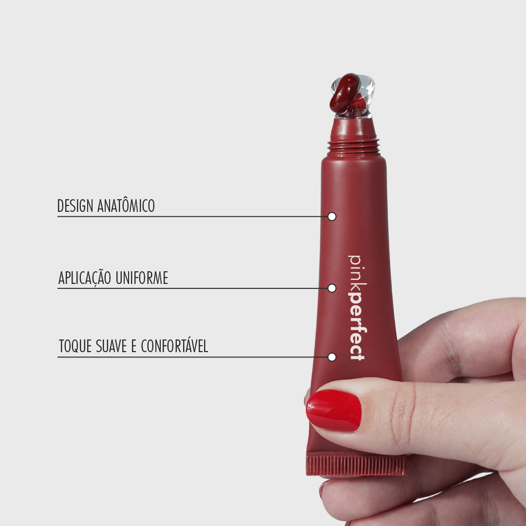 Mão segurando lip balm vermelho com aplicador anatômico e textura cremosa para cuidados labiais.