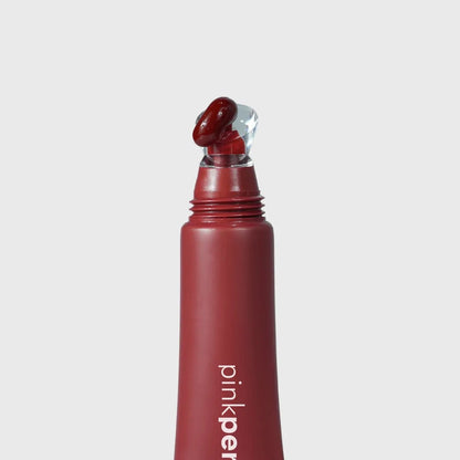 Aplicador labial vermelho com ponta transparente, produto para cuidados labiais, fundo claro.